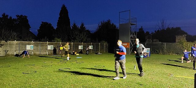 Feuerwehr-Fitnesstraining am Abend auf der beleuchteten Rasenfläche
